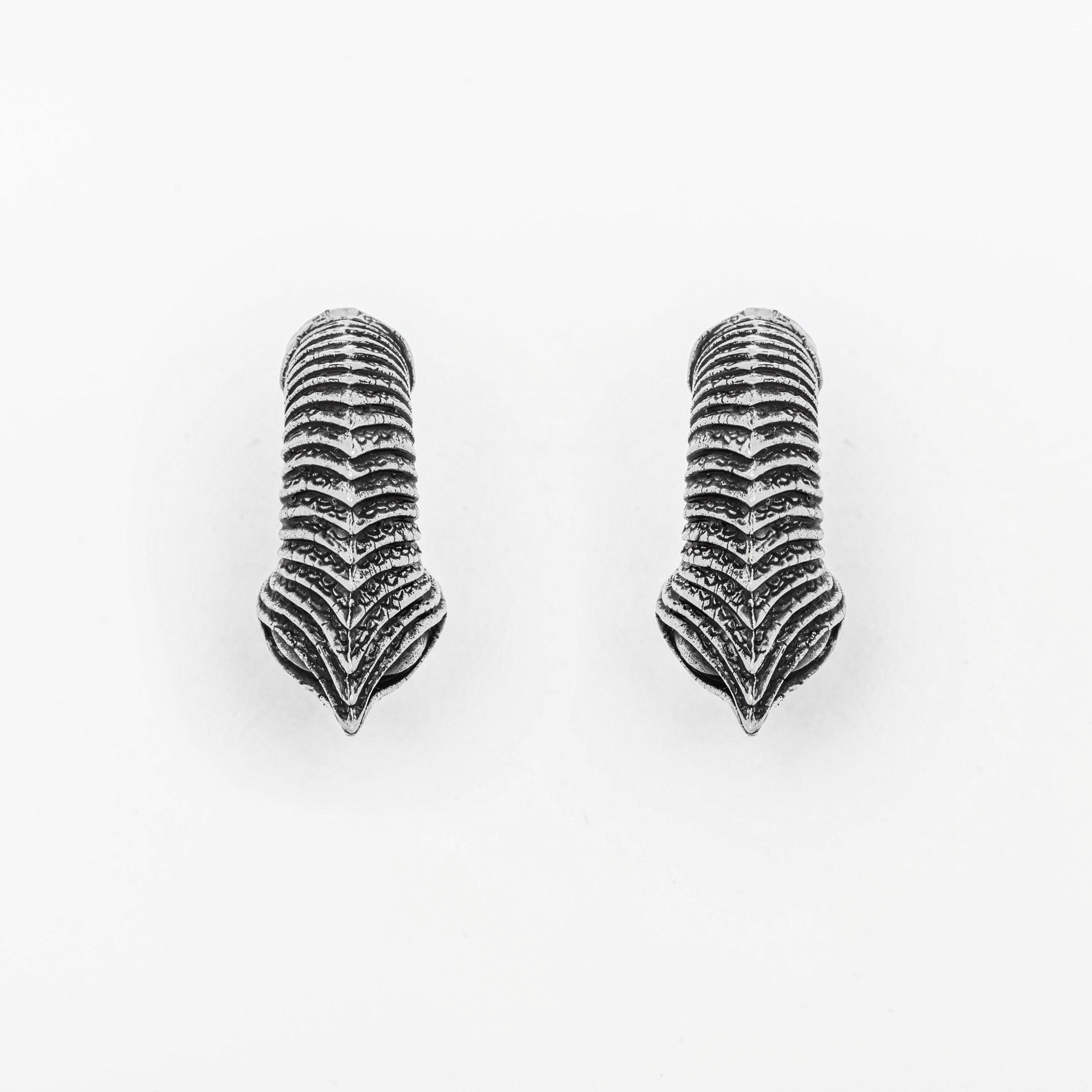 The MARVDASHT Medium Cyborg Clicker Ear Weights in 925 Silver by Kaya Movement showcase detailed engravings in a dark metallic finish, set against a clean white background. These dystopian pieces of body jewelry emphasize the intricate texture and structure of bird claws.